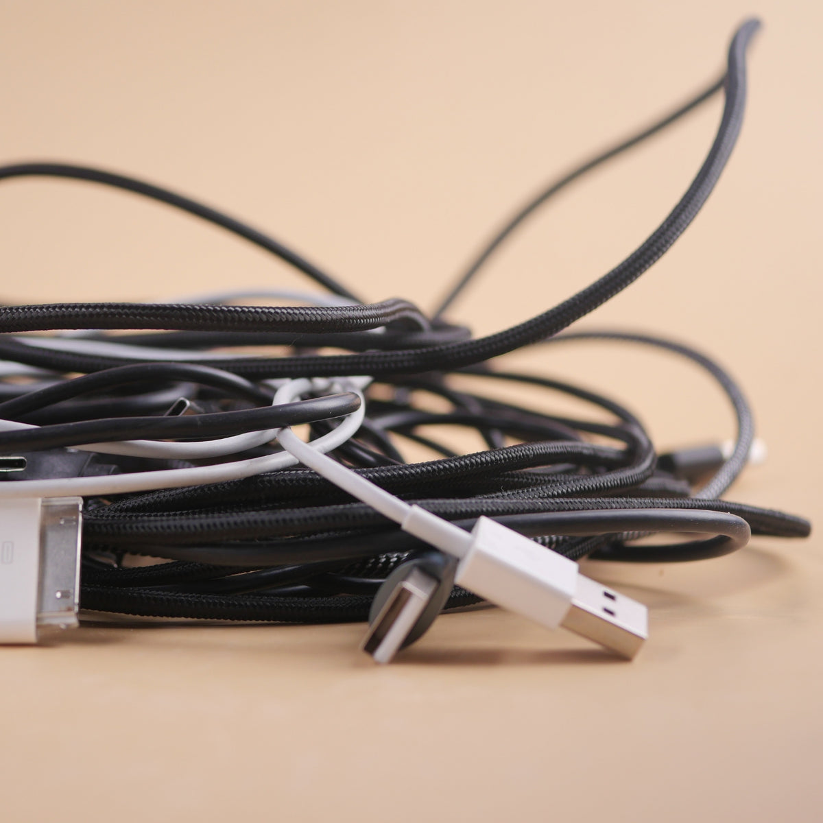 Lose USB- und Ladekabel auf einem Holztisch als Beispiel für Kabelsalat im Alltag