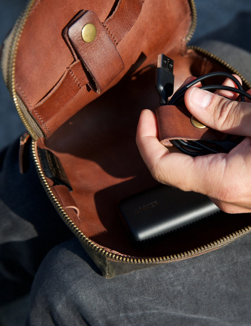 Geöffnete Kabeltasche mit Lederfutter, aufgerolltem USB-Kabel und Powerbank