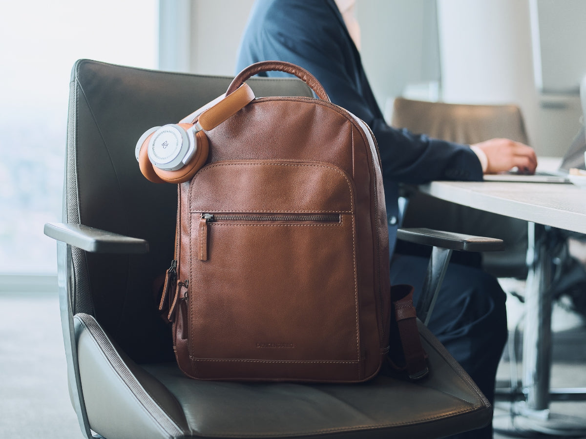 Sac à dos ordinateur marron avec un casque audio à côté d’un poste de travail