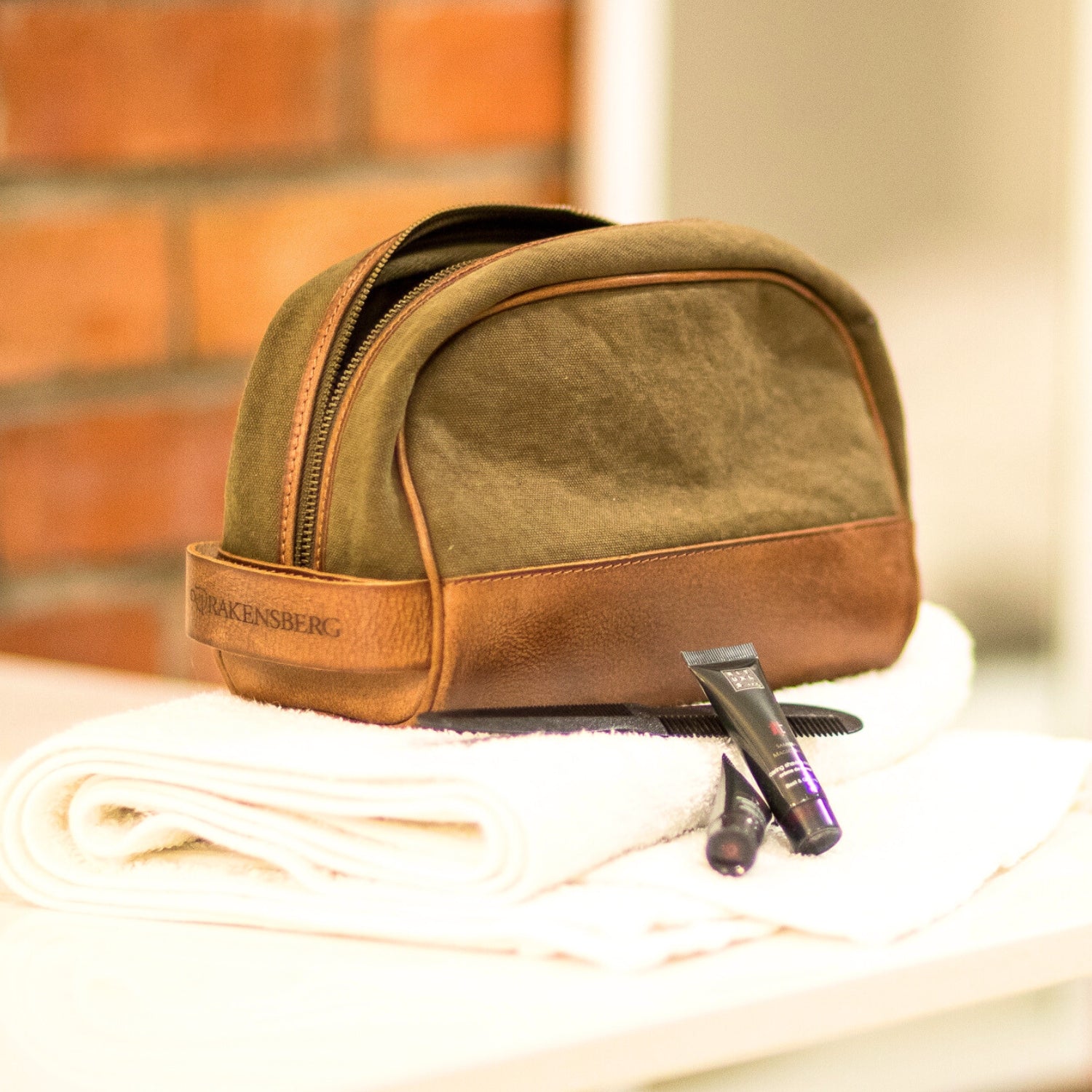 Kulturbeutel aus Leder von Drakensberg liegt auf einem Stapel Handtücher im Badezimmer