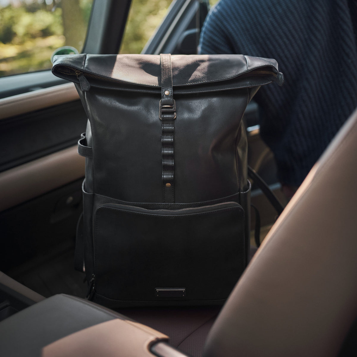 Arthur leather laptop backpack in Vintage Black – placed on a car seat