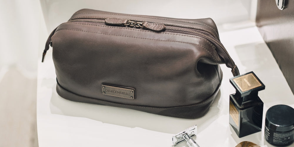 Trousse de toilette Ruby en cuir brun café avec accessoires de rasage près d’un lavabo
