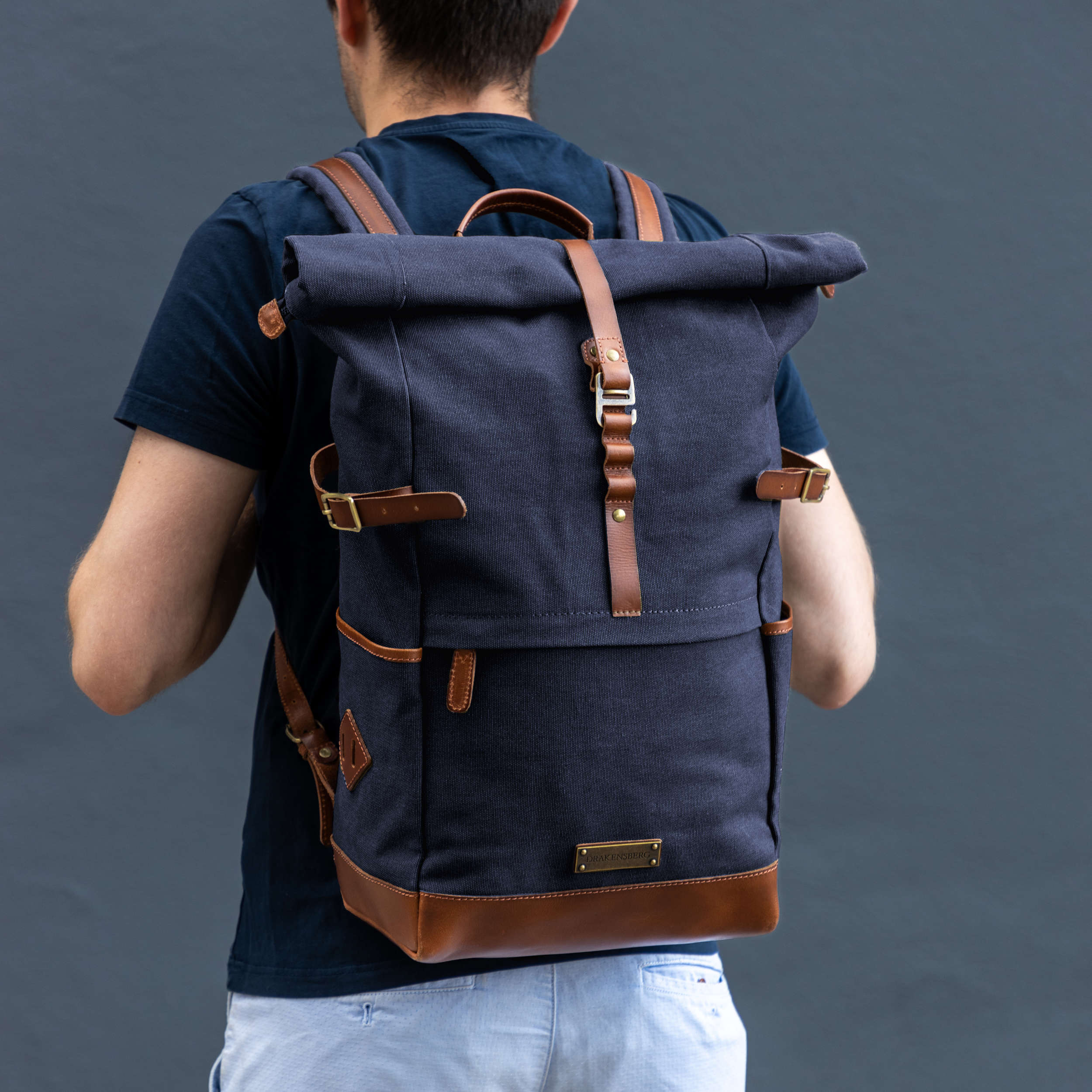 Model trägt Canvas Rucksack Wyatt mit Leder-Elementen für Herren und Damen, handgemacht und nachhaltig, dunkel-blau