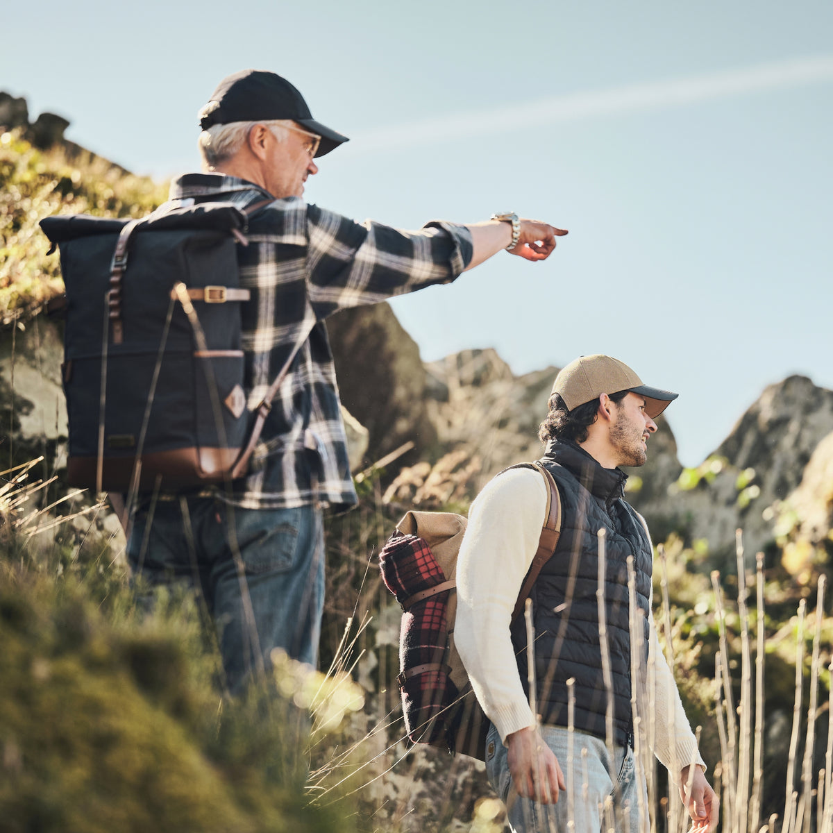Two hikers carrying Wyatt backpacks in Navy Blue and Khaki Beige on a rocky trail.