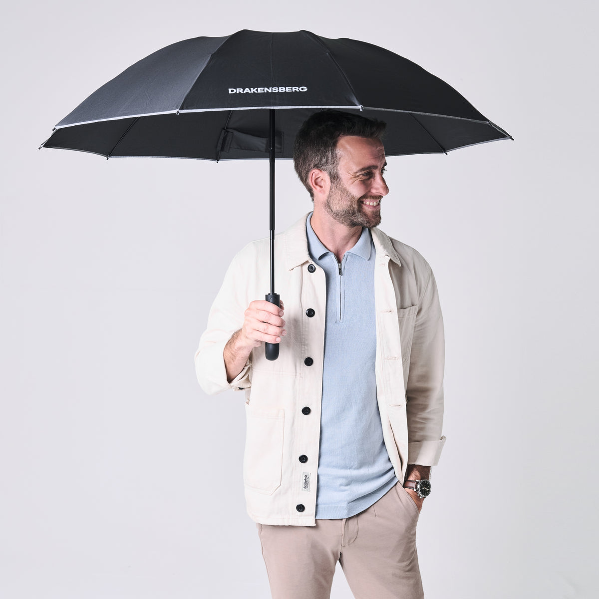 Mann mit geöffnetem schwarzen Automatik-Regenschirm Nimbus von DRAKENSBERG