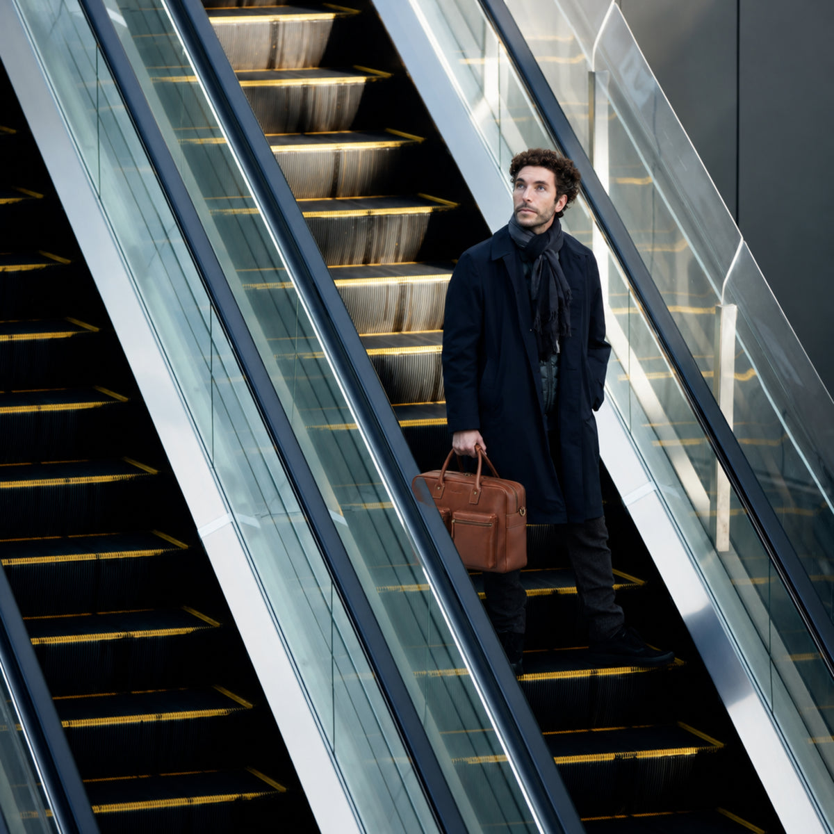 Businessperson auf einer Rolltreppe mit der 48h-Aktentasche Angelo