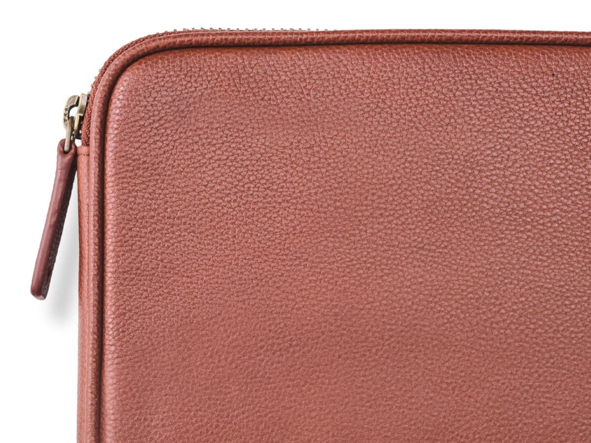 Detail of the grained leather surface and metal zip on the Porto cable organiser in Chestnut Brown