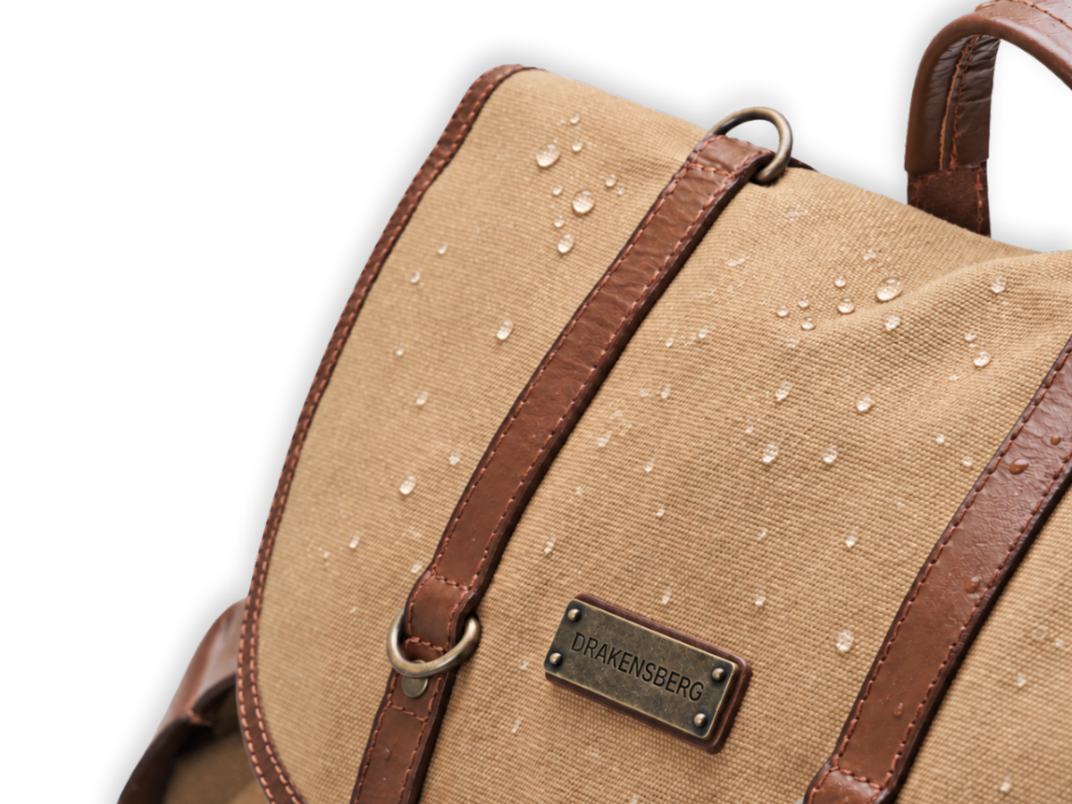 Gouttes de pluie sur le rabat en toile de Henry kaki beige, près des sangles de fermeture en cuir.