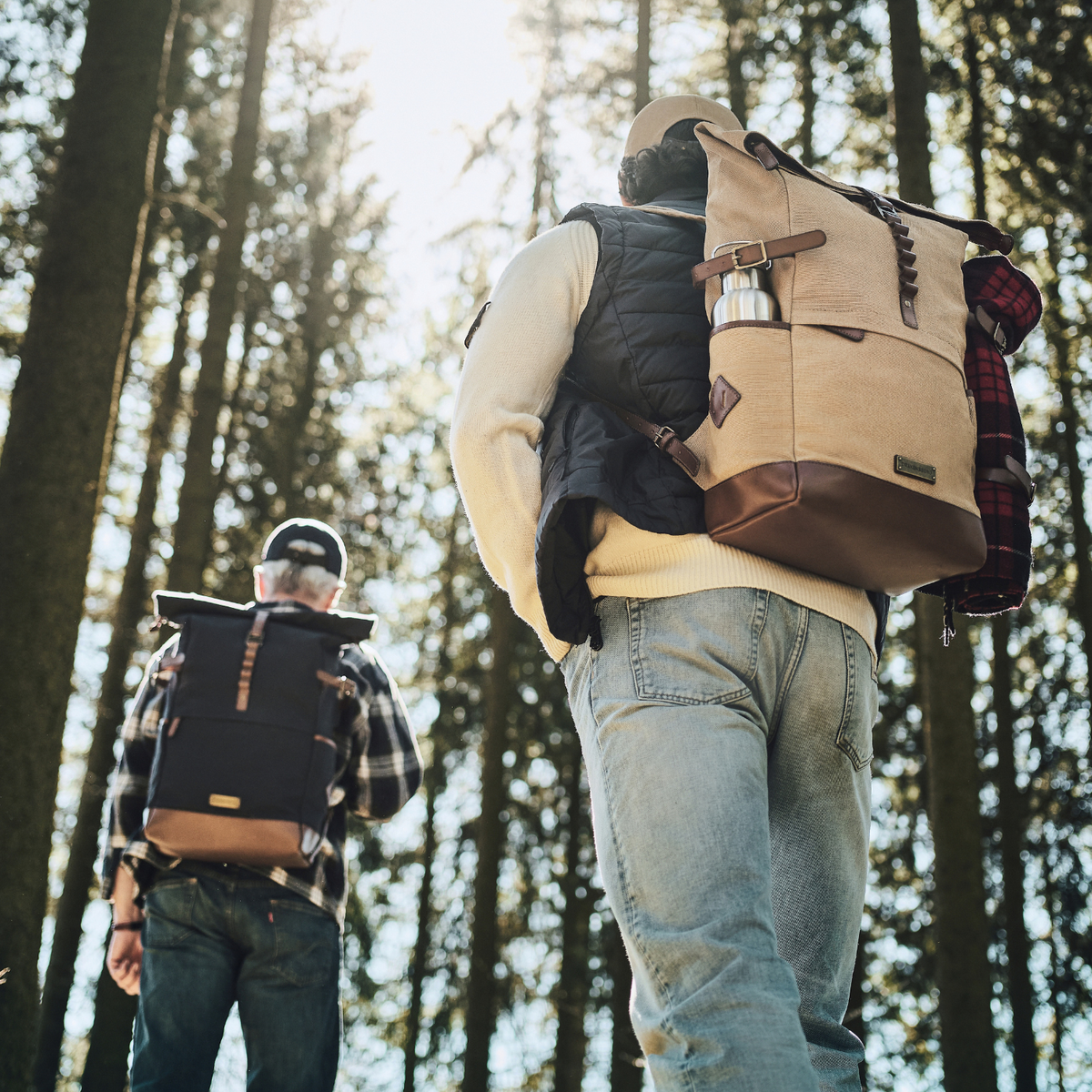 Zwei Wanderer mit Rucksäcken Wyatt in Khaki-Beige und Marine-Blau auf einem Waldweg.