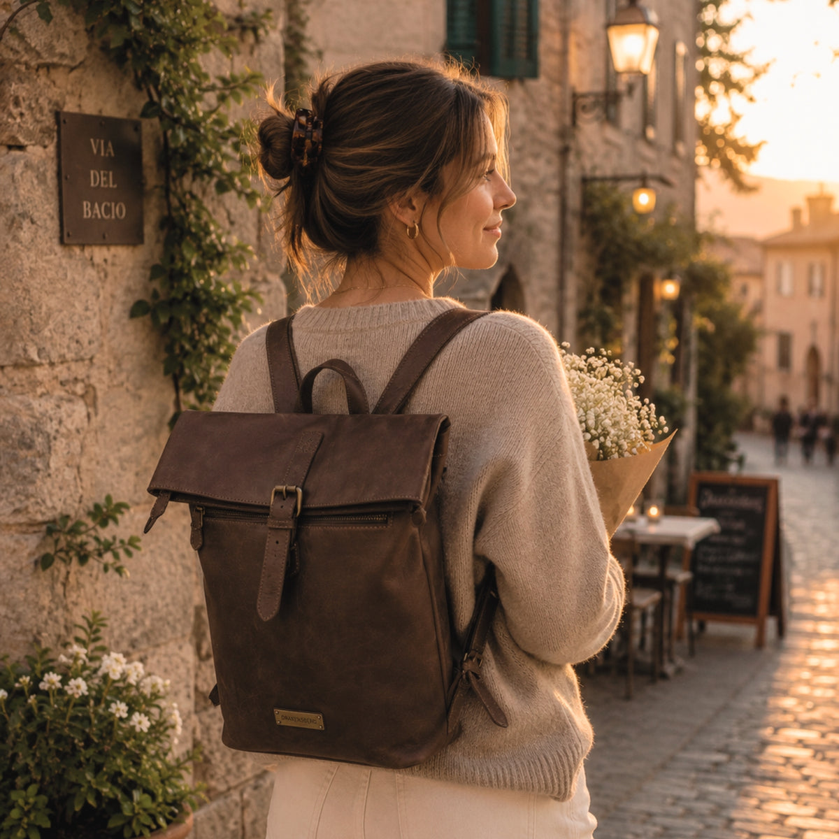 Frau mit braunem Lederrucksack Paula in einer Gasse im Abendlicht