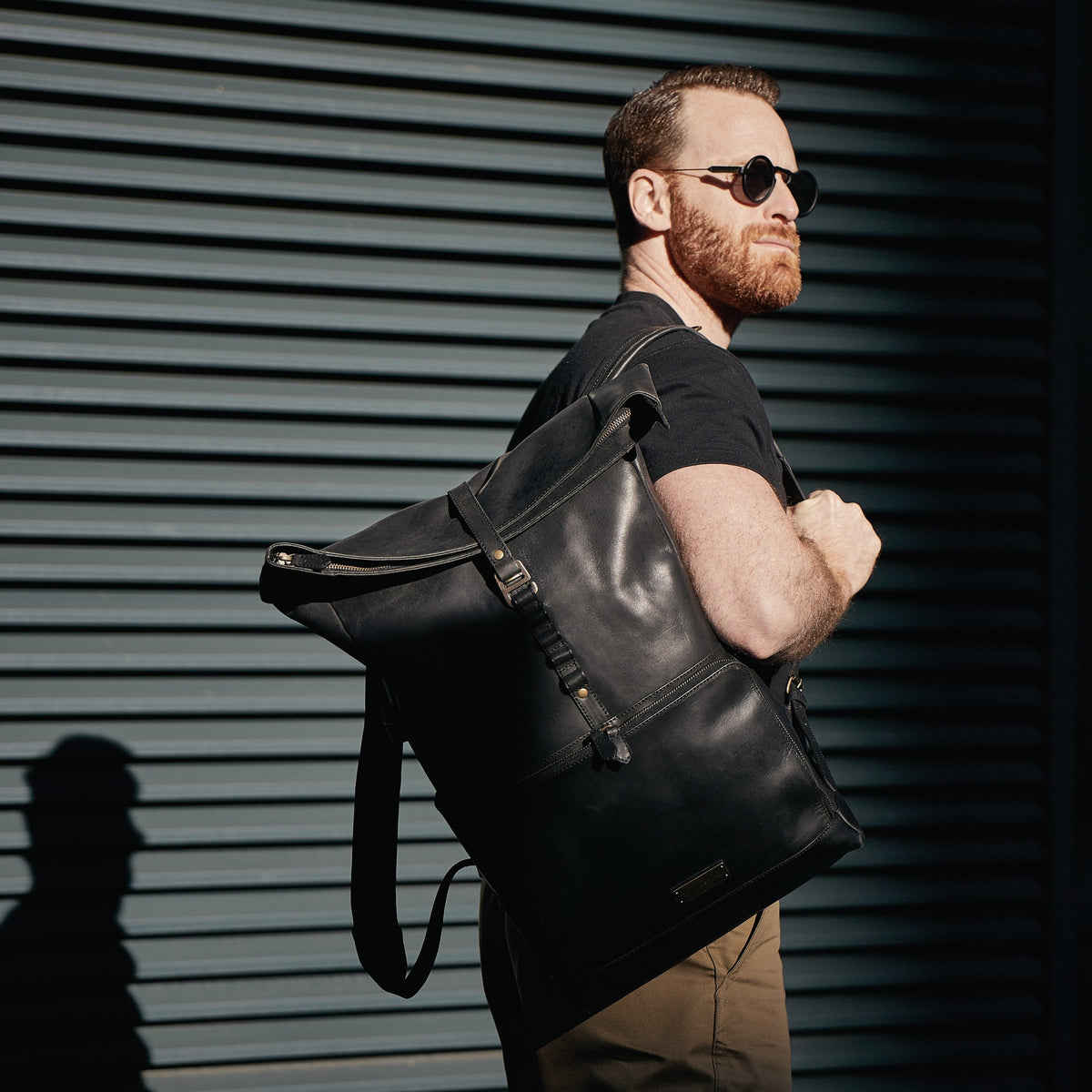 Arthur leather laptop backpack in Vintage Black – man carrying the backpack over one shoulder