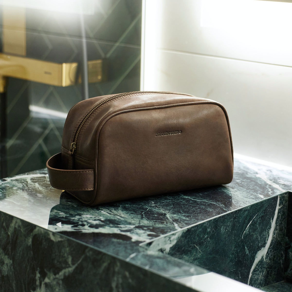 Brown Theo leather toiletry bag on a marble bathroom counter