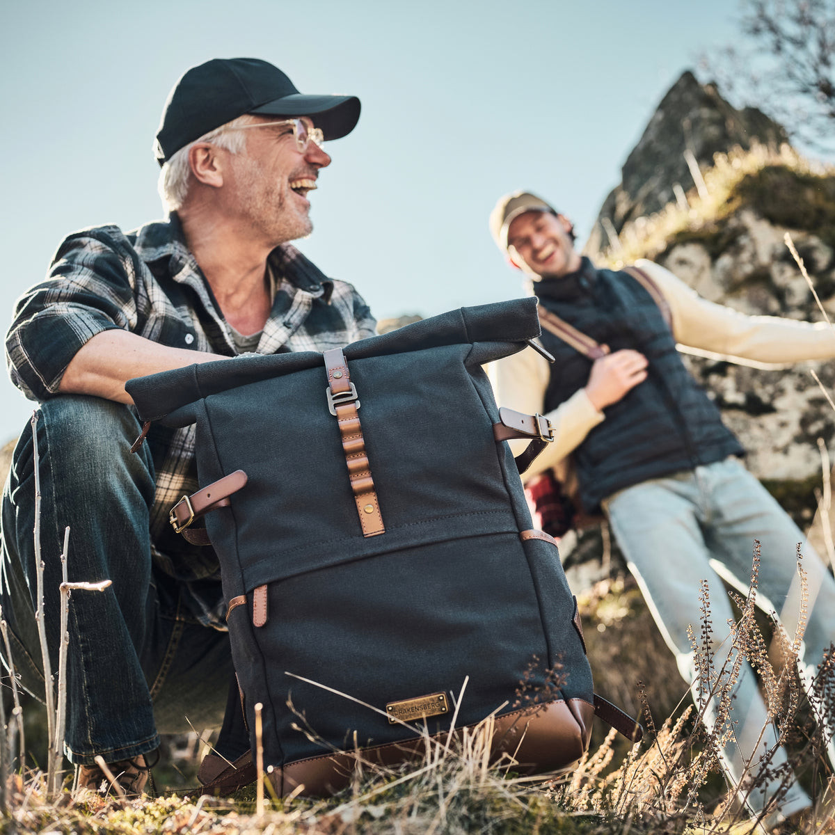 Wyatt backpack in Navy Blue in front of two hikers resting in rocky terrain.