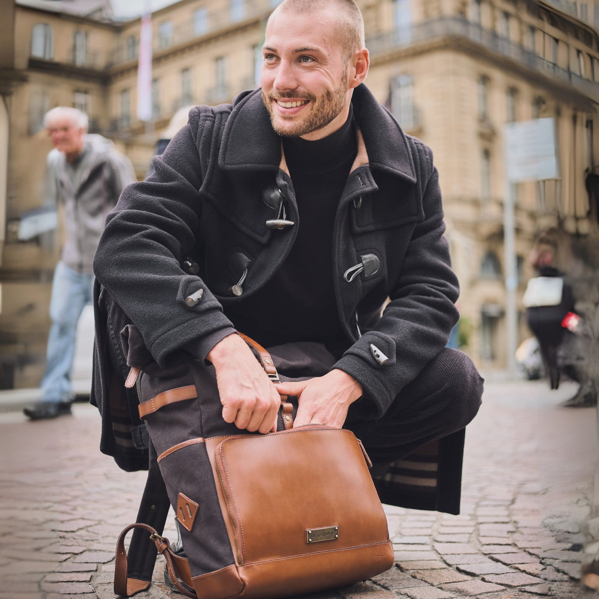 Sac à dos ordinateur Arthur en toile et cuir Noir – homme avec le sac sur un banc en ville