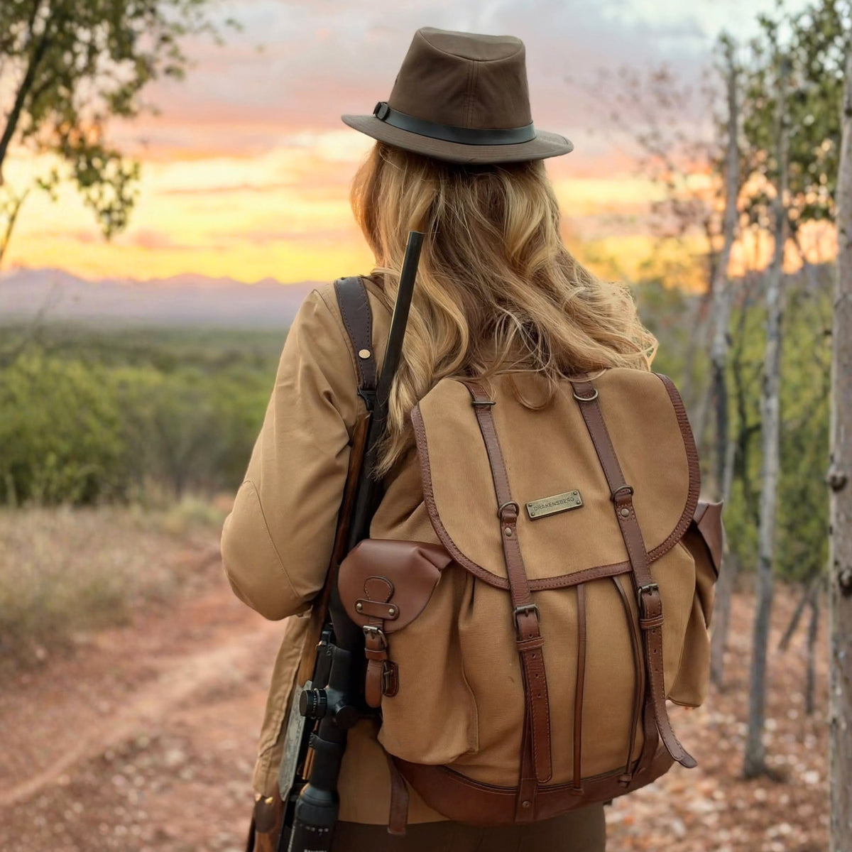 Henry backpack in Khaki Beige, worn by a person with a hat on a woodland path at sunset.